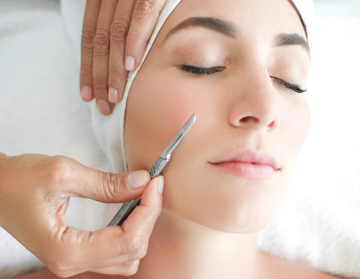 Woman receiving a facial treatment with a tool on a white background