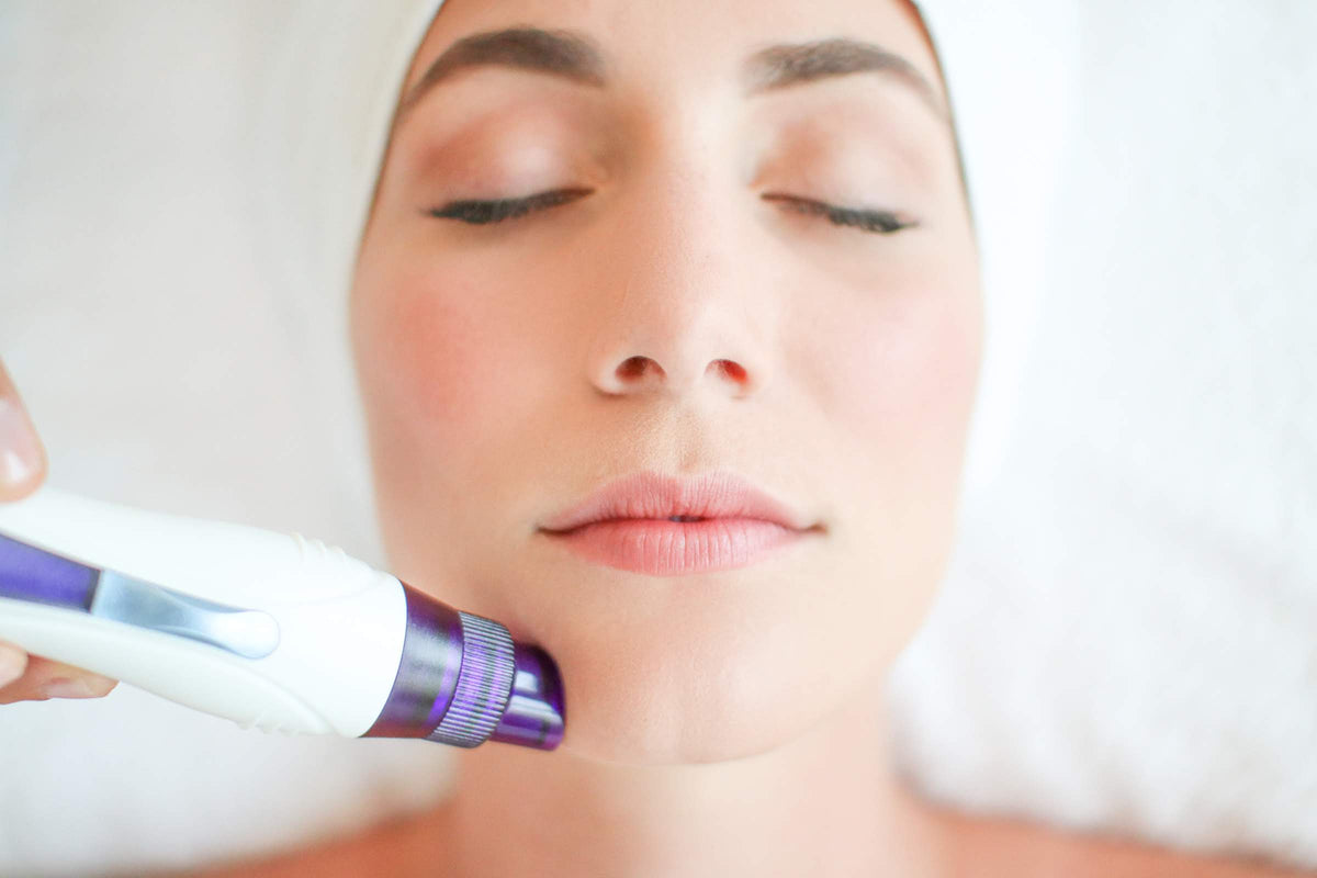 Woman receiving facial treatment with purple skincare device for luxury skin care routine